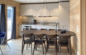 Eine moderne Küche mit Holzschränken, einem Esstisch mit Stühlen und einer Pendelleuchte.