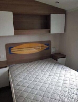 Ein Schlafzimmer mit einem Bett, einem Holzkopfende, einem Nachttisch und einem Wandregal.