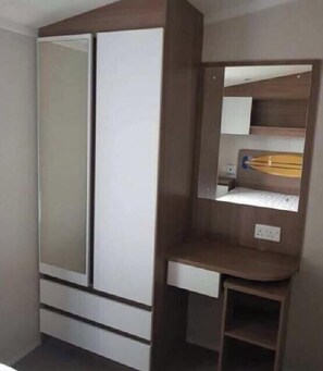 Ein Zimmer mit Kleiderschrank, Schreibtisch und Spiegel.