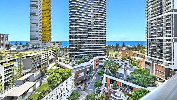 A modern urban area with high-rise buildings, a central plaza, and a view of the sea. - Beach Fun at Oracle Level 10 (Gold Coast)