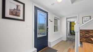 A hallway with a blue door, a framed picture, a staircase, and a door leading to another room. - Peaceful Stay with Town Cove Access (Eastham)