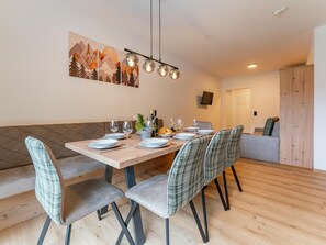 A dining area with a wooden table set for four, surrounded by upholstered chairs. - Charming apartment directly on the slopes. (Hinterglemm)