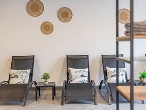 A room with three reclining chairs, each with a cushion featuring a mountain scene. There are three woven wall hangings above the chairs. - Charming apartment directly on the slopes. (Hinterglemm)