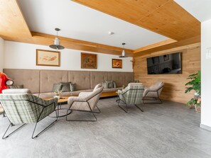 A modern living room with a sofa, two armchairs, a coffee table, and a TV mounted on the wall. - Charming apartment directly on the slopes. (Hinterglemm)