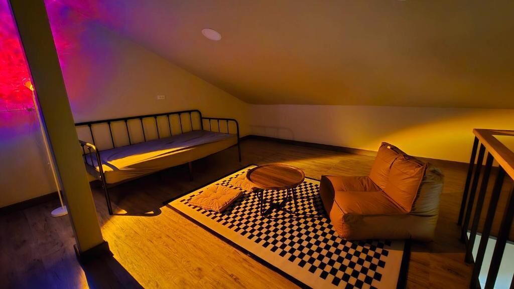 A cozy room with a bed, a sofa, a checkered rug, and a small table.