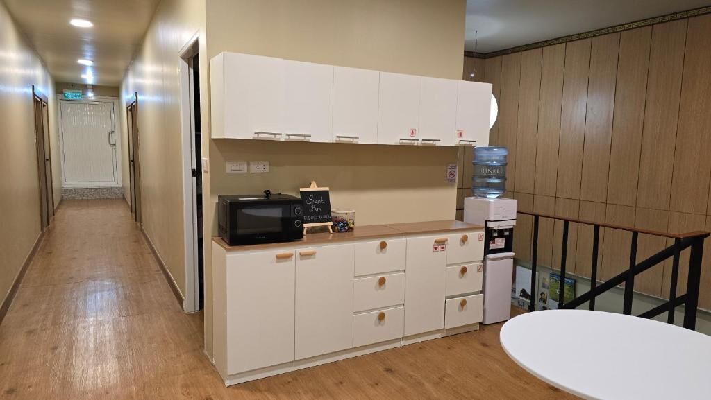 A hallway leading to a kitchenette with a microwave, cabinets, and a water dispenser.
