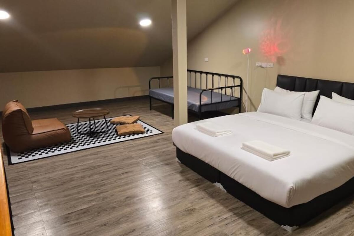 A bedroom with a bed, a chair, a small table, and a bunk bed.