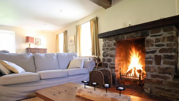 A living room with a stone fireplace, a sofa, a wooden coffee table, and a lamp. - Large cottage near the Fagnes and Francorchamps. (Francorchamps)
