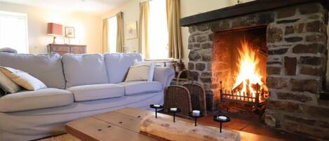 Una sala de estar con chimenea de piedra, un sofá, una mesa de centro de madera y una lámpara.