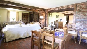 A room with a bed, a wooden table, and a brick wall. - Large cottage near the Fagnes and Francorchamps. (Francorchamps)