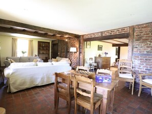 Ein Zimmer mit einem Bett, einem Holztisch und einer Backsteinwand.