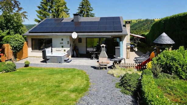 Une maison dotée d’un patio couvert, d’un espace barbecue et d’un toit équipé de panneaux solaires.