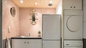 Une cuisine compacte équipée d’un évier, d’un miroir, d’un réfrigérateur et d’un lave-linge.