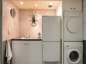 Eine kleine Küche mit Spüle, Spiegel, Kühlschrank und Waschmaschine.