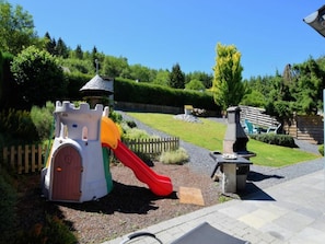 Ein Spielplatz mit einer Burg-Spielkonstruktion, einer Rutsche und einem Grillplatz.