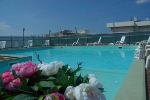 Ein Schwimmbecken mit Liegestühlen und einer Blumenkomposition.