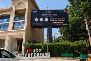 A billboard advertising Montefiori luxury residences with an easy payment plan, a site office address, and contact information. - Aerohub Suites: Himalayan Foothills Escape Cozy 1BHK in Zirakpur, NearChandigarh (Zirakpur)