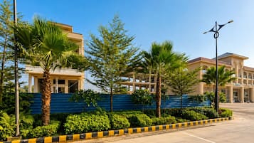 A modern building with a blue wall and palm trees in front.