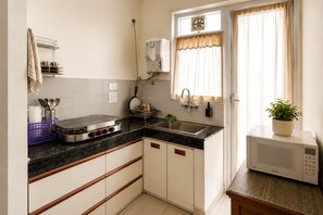 A compact kitchen with a gas stove, sink, and microwave. - Aerohub Suites: Himalayan Foothills Escape Cozy 1BHK in Zirakpur, NearChandigarh (Zirakpur)