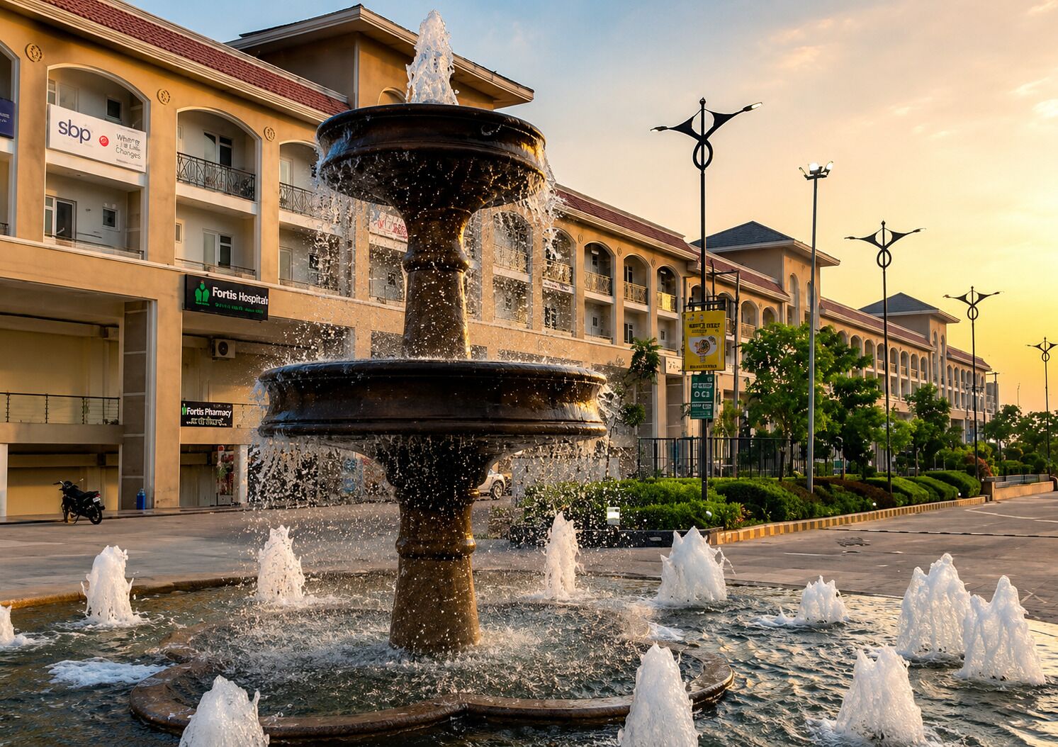 Ein Springbrunnen mit mehreren Wasserstrahlen auf einem Platz, im Hintergrund Gebäude.