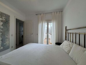 Une chambre avec un lit, une porte donnant sur un balcon et une vue sur l’extérieur.