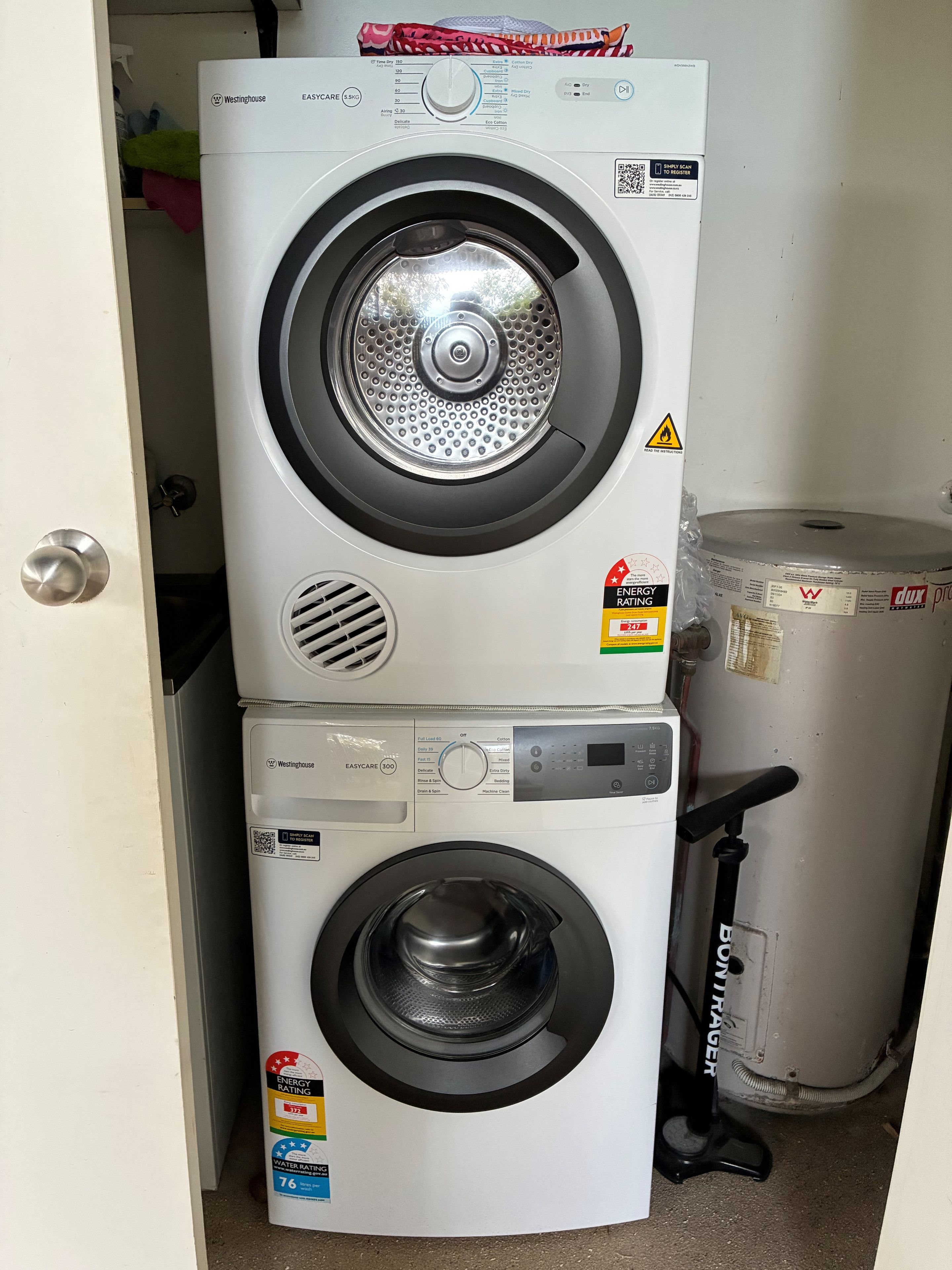 Un appareil combiné lave-linge et sèche-linge, de type « superposé », muni d’étiquettes indiquant sa consommation d’énergie et d’eau.