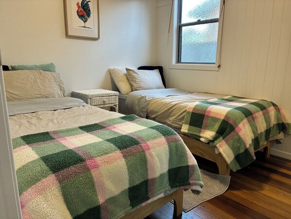 A bedroom with two beds, a window, and a framed picture on the wall.