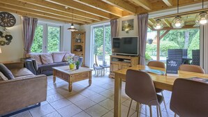 A cozy living room with a sofa, coffee table, TV, and dining area with chairs. - Home in a private park with a spacious garden (Epe)
