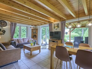 A cozy living room with a sofa, coffee table, TV, and dining area with chairs. - Home in a private park with a spacious garden (Epe)