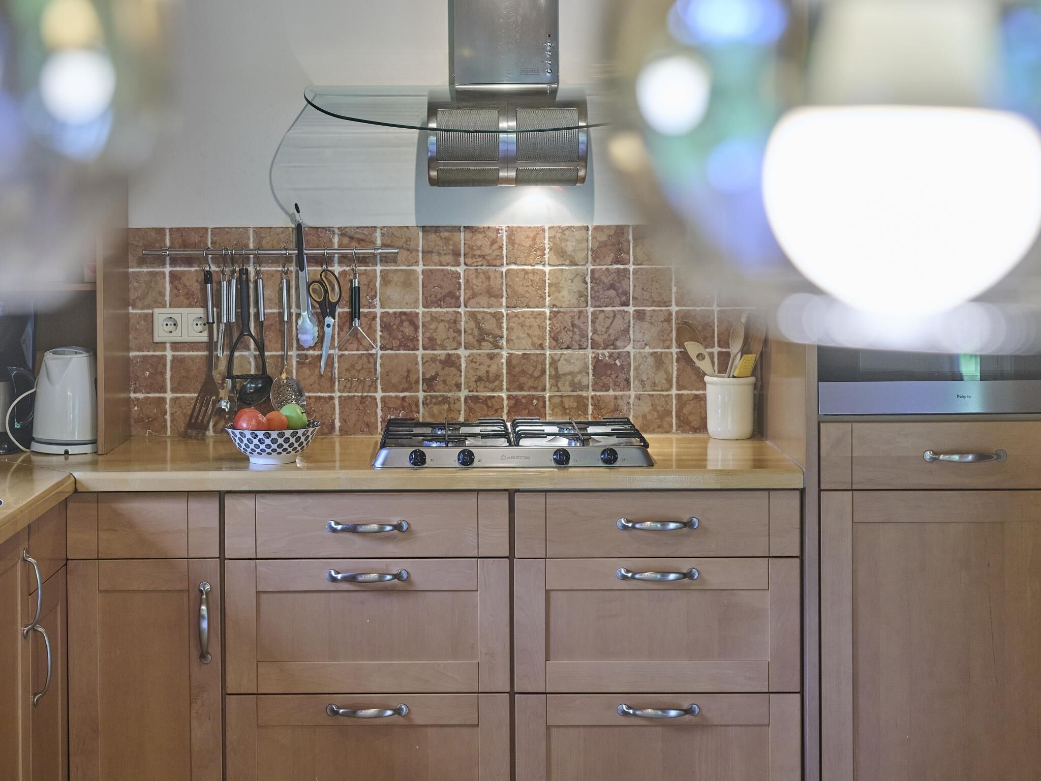 A kitchen with a gas stove, wooden cabinets, and a tiled backsplash.