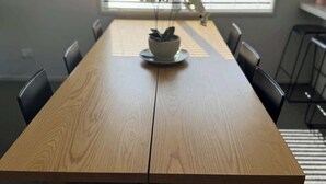 A wooden dining table with chairs, a potted plant, and a window with blinds. - Bedroom (Jack's Point)