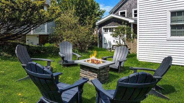 A backyard with a stone fire pit surrounded by four Adirondack chairs. - Winter Harbor Haven - NEW! (Winter Harbor)
