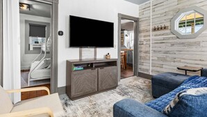 A modern living room with a flat-screen TV, a sofa, a chair, and a built-in entertainment unit. - Winter Harbor Haven - NEW! (Winter Harbor)