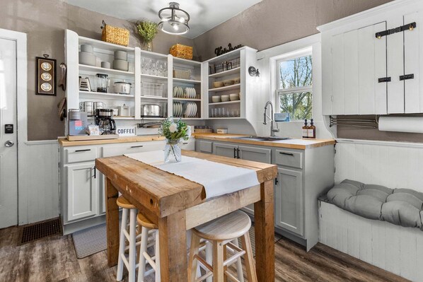 A kitchen with white cabinets, a wooden table, and stools.