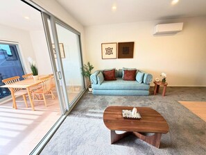 Ein Wohnzimmer mit einer Couch, einem Couchtisch und einem Essbereich mit Stühlen und einem Tisch.