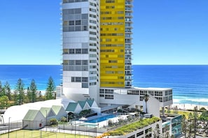 Ein Hochhaus-Hotel mit mehreren Balkonen, einem Schwimmbecken und Blick auf den Ozean.
