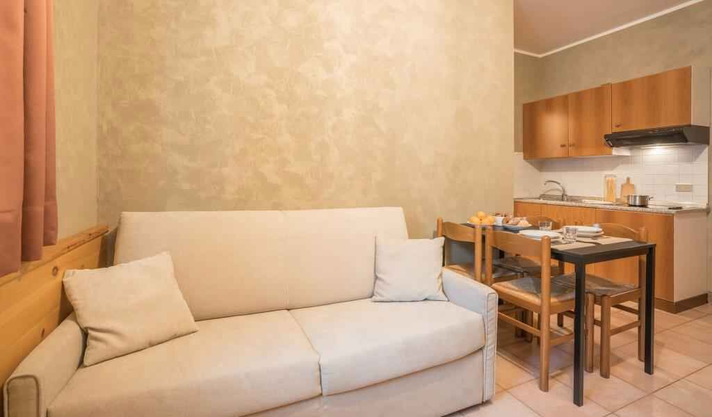 A living room with a sofa and a dining table with chairs.