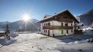 Ein Chalet mit Balkon, umgeben von Schnee und Bergen.