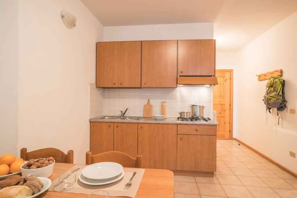 A compact kitchen with wooden cabinets, a sink, and a dining area with a table set for two.