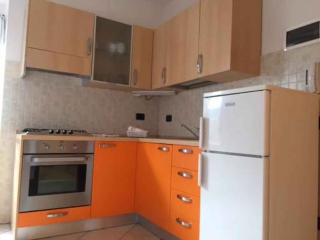 Een keuken met houten kastjes, een roestvrijstalen oven en een witte koelkast.