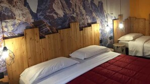 Une chambre avec une tête de lit en bois, un lit recouvert de linge de maison blanc et une fresque représentant une montagne sur le mur.