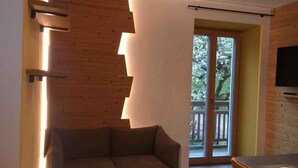 Un salon moderne avec un canapé, une table à manger et un téléviseur fixé au mur.