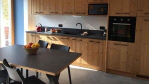 Une cuisine moderne avec des meubles en bois, un plan de travail noir et une table à manger avec des chaises.