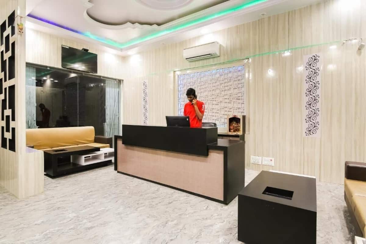 A reception area with a black reception desk, a sofa, a TV, and a decorative wall with a patterned design.