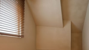 Un escalier étroit avec une petite lucarne donnant sur un espace extérieur.
