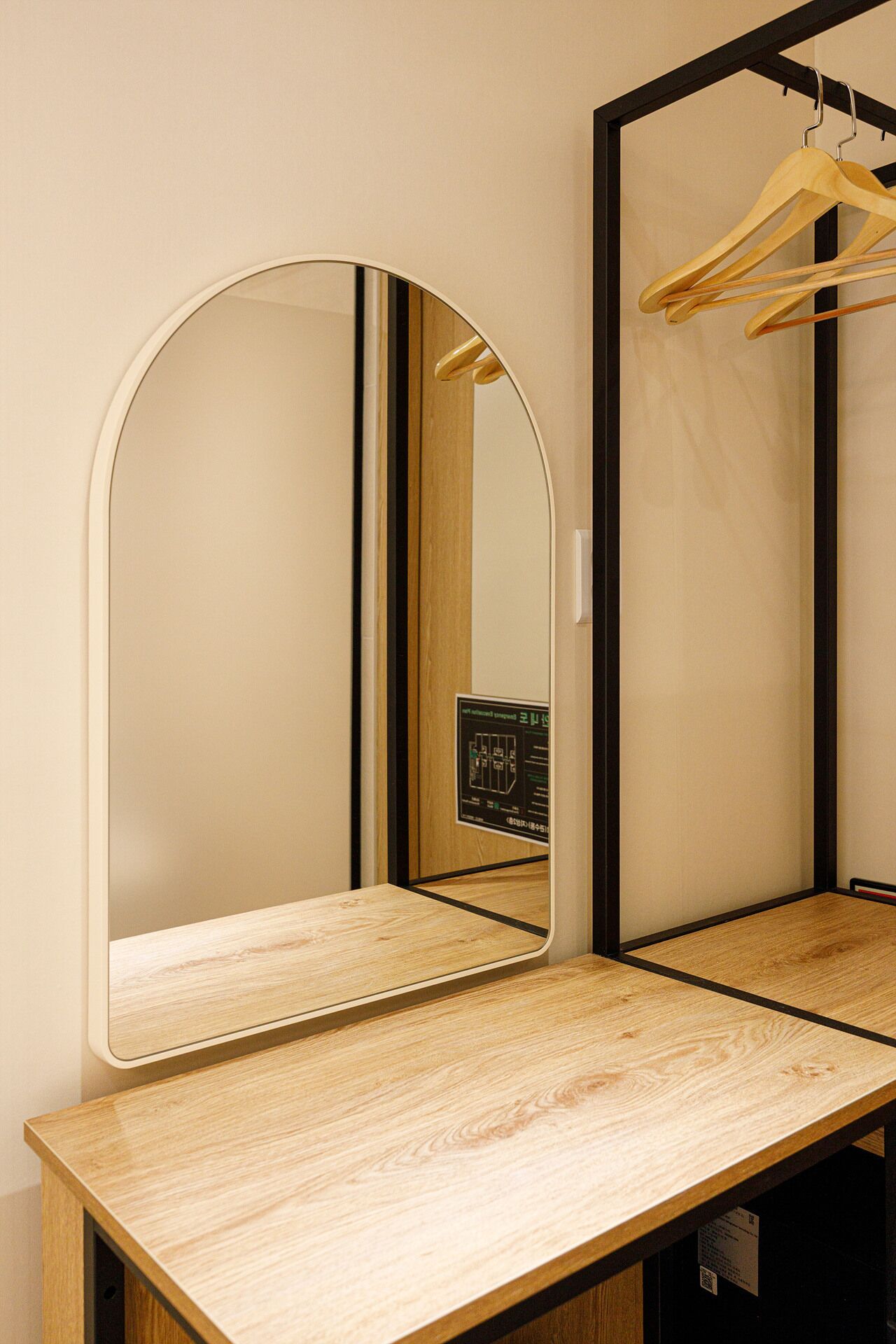 Un miroir avec un cadre en bois, une table en bois et un cintre en bois.