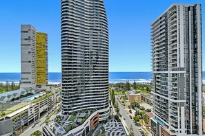 A modern high-rise building with a curved facade, a parking garage, and a view of the ocean. - Ocean Views at Oracle Level 17 (Gold Coast)