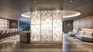 Un hall d’hôtel moderne doté d’un bar, de coins salon et d’un grand mur décoratif.