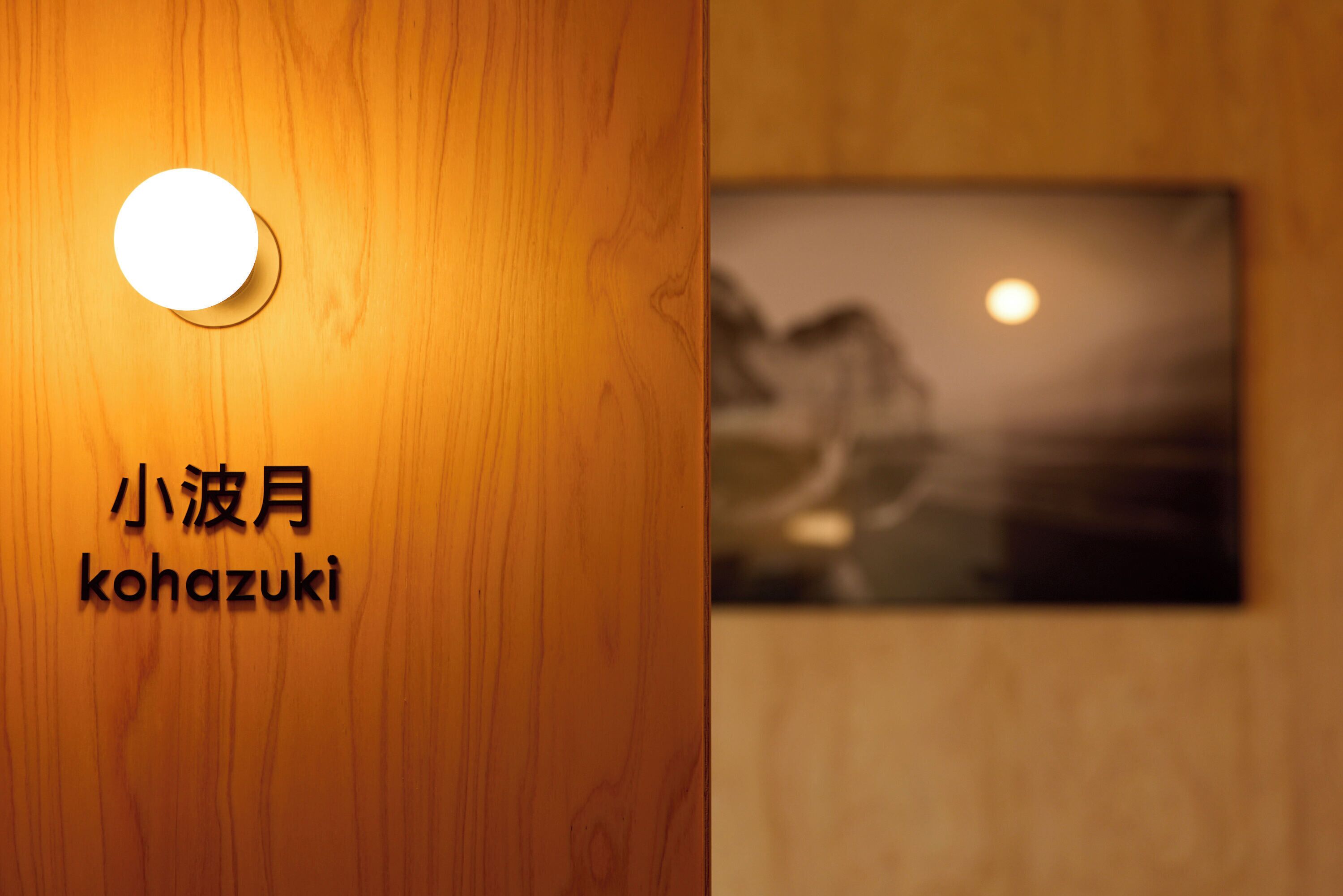 A wooden wall with a circular light fixture and a framed picture with a moon and landscape.