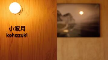 A wooden wall with a circular light fixture and a framed picture with a moon and landscape.